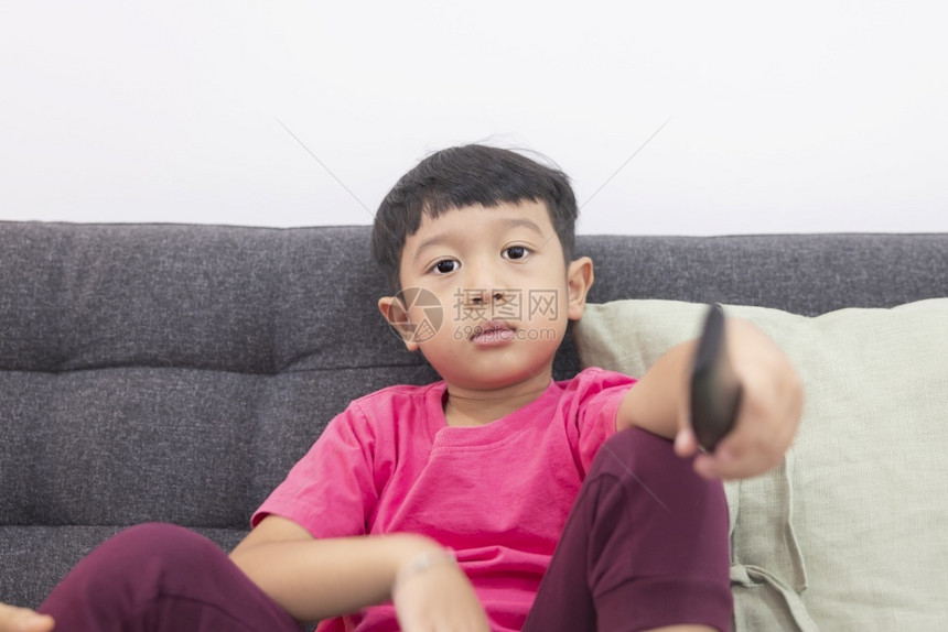 享受人们运动微笑的小男孩看电视按遥控器在客厅舒适沙发上拉着遥控器在数字智能电视上玩游戏愉快乐的小孩使用最喜爱的乐子图片