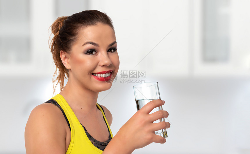 健康的生活概念美丽和年轻女在厨房复制空间的模糊背景上拿着玻璃杯用淡水装着玻璃新鲜品尝锻炼图片