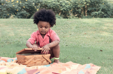 绽放户外初级一名非洲男孩在后院打和开篮子吃午饭图片