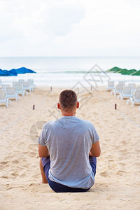 坐在沙滩上的男人背影图片