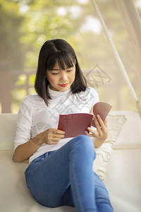 年青的亚洲女在阅读一本书学生习户外图片