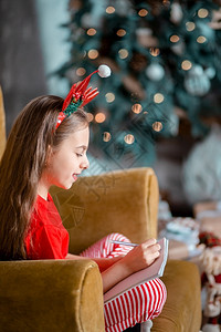 沙发上头戴圣诞装饰的可爱女孩写信图片