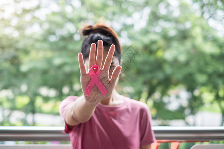 穿T恤妇女手握粉丝带预防癌症概念图片