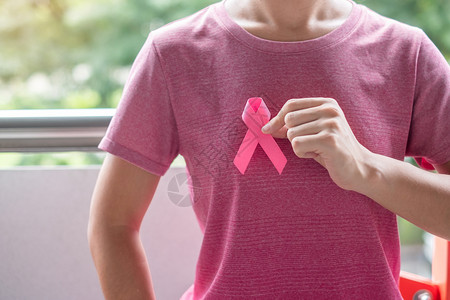 穿粉红色T恤妇女手握粉丝带预防癌症概念图片