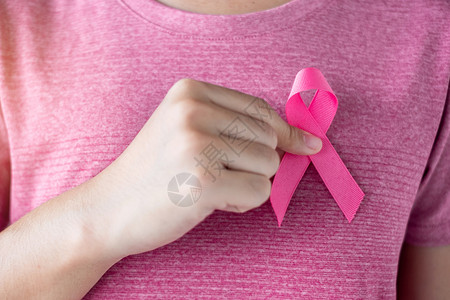 穿粉红色T恤妇女手握粉丝带图片