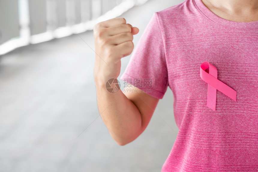 身穿粉红色T恤的妇女佩戴粉丝带预防癌症概念图片