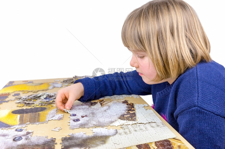 学习年轻的caucasian年轻女孩制作拼图在桌子上猫的拼图孤立在白色背景上的智慧图片