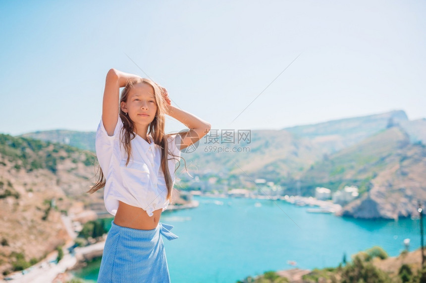 地平线经过天空穿着山上漂亮的岩石和海边裙子的可爱女孩美丽的大自然小女孩在山顶享受谷风景的小女孩在山顶图片