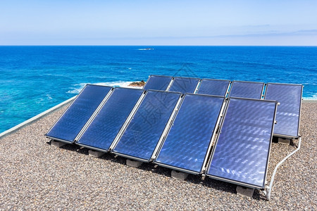 海洋水附近屋顶上的一组蓝色太阳能电池板家岛经济图片