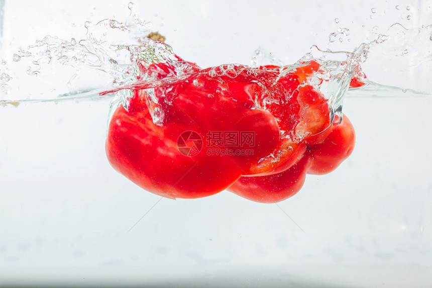 甜辣椒在水中喷洒红辣椒在白色背景的面上加红甜辣椒是一种不降低沙拉烹饪图片
