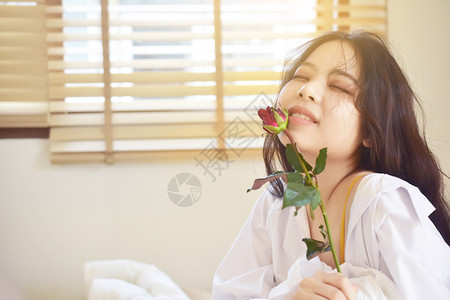 美丽容女穿着玫瑰的白衬衫在床上卧室年轻女子可爱的微笑在情人节的概念头发脸图片