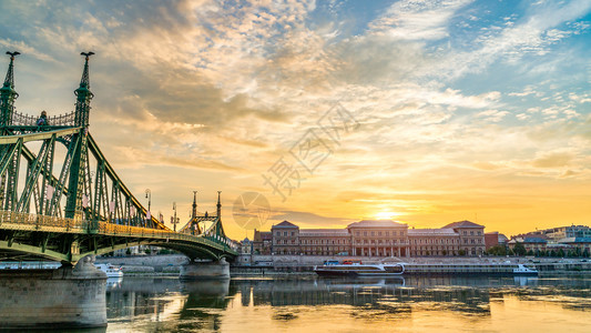 路暮旅游的布达佩斯自由桥和旅游船在日出自由桥和船只上的航行情况图片