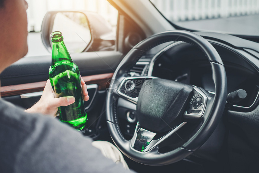 合法的醉酒男子驾驶一辆汽车在路上载着啤酒瓶的车危险醉酒驾驶概念威士忌酒男人图片