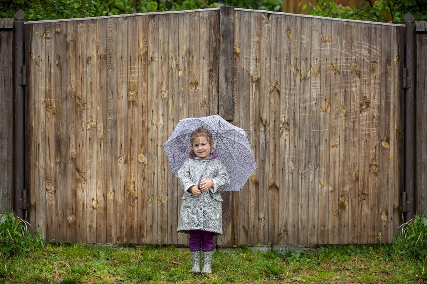 落下雨衣夏天走在中的小女孩打着雨伞水坑夏天走在雨中的小女孩打着雨伞玩图片
