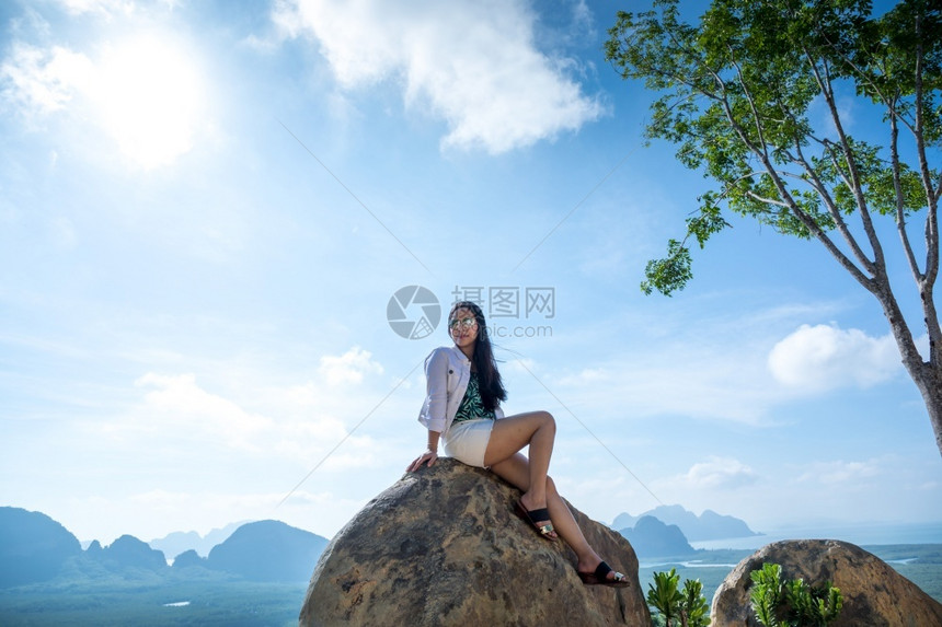 活动户外海坐在泰国SamedNangChee的PhangNgaBay山顶上的年轻女子图片