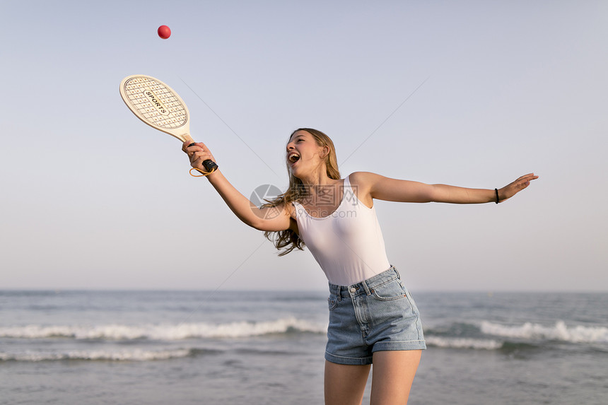 在海滨附近玩网球的快乐女孩复制球拍快乐的图片