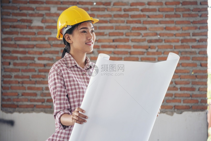 工人女建筑程师在地身戴安全白色钢帽的建筑工场薪女程师土木带有硬帽子安全头盔的女建筑工程师概念a妇女建筑工程师行业写作图片