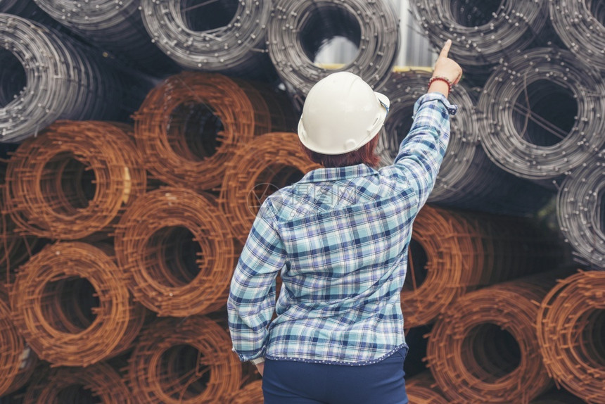 商业工作人们女建筑工程师在地身戴安全白色钢帽的建筑工场薪女程师土木带有硬帽子安全头盔的女建筑工程师概念a妇女建筑工程师图片