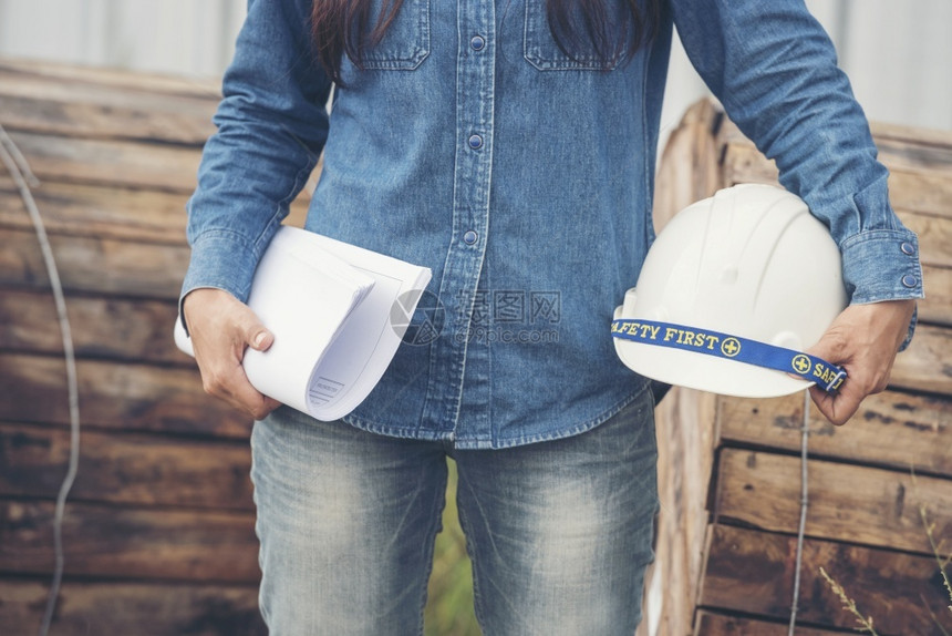 项目建设者工作女筑程师在地身戴安全白色钢帽的建筑工场薪女程师土木带有硬帽子安全头盔的女建筑工程师概念a妇女建筑工程师图片