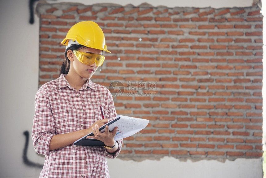 女建筑工程师在地身戴安全白色钢帽的建筑工场薪女程师土木带有硬帽子安全头盔的女建筑工程师概念a妇女建筑工程师牛仔裤项目地点图片