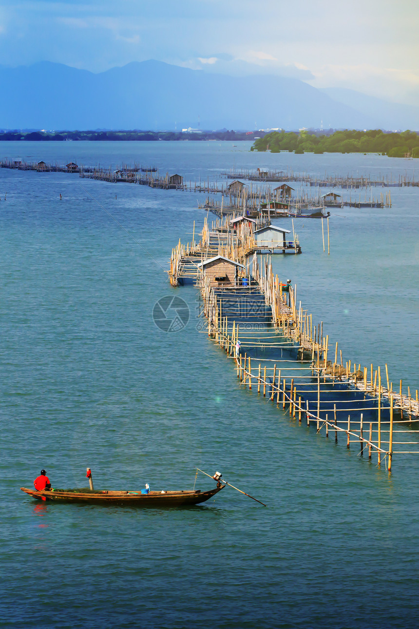 社区海岸线乡村的日出时在沿海滨养鱼笼的风景一名亚洲年长农民将咸水鱼喂养在笼中泰国钱塔布里农村场景图片
