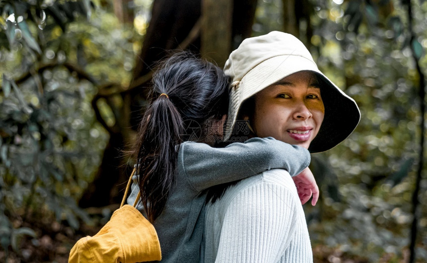 森林一个疲累的小女儿在假期旅行时带着她的母亲在树林里骑着一只小猪的背去散步为了家庭概念参加探险活动一种季节图片