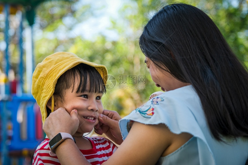 美丽的伤心嘲弄快乐年轻母亲在夏日公园里捏着女儿的脸颊家人一起度过节假图片