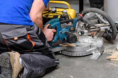 修理男人内部的占领概念建筑工人在地板上操作一个切割刀的机图片