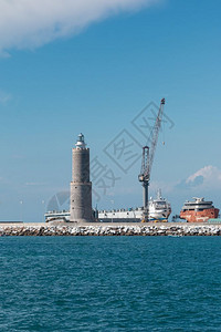 船厂货物外部海中白帆船和灯塔附近坞工作时的Crane图片