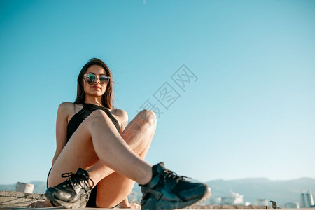 城市闲暇穿着黑色运动鞋短裤和的头发女孩坐在一栋高楼屋顶上自由图片