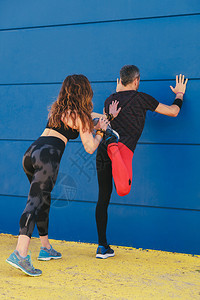 肌肉发达户外年轻情侣在蓝墙前拉一起然后奔跑年轻的图片