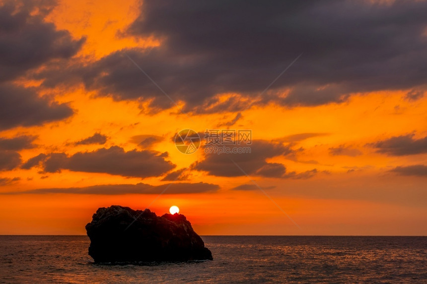 在一片宁静的海中太阳落在孤寂的岩石上独子和惊人海日落颜色出洋晚上图片