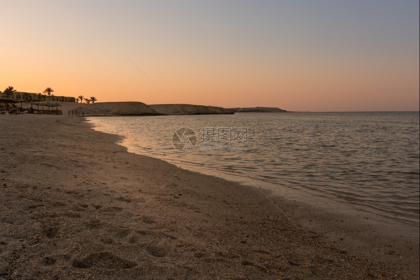 岛海洋日落时美丽的埃及海滩背景有棕榈树和阳伞巡航图片
