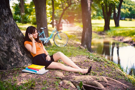 女人用耳机在公园的树下休息放松概念自行车时尚人们图片