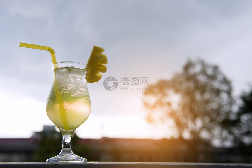 蓝色的柳条橙菠萝鸡尾酒和切片在夕阳夏日的概念图片