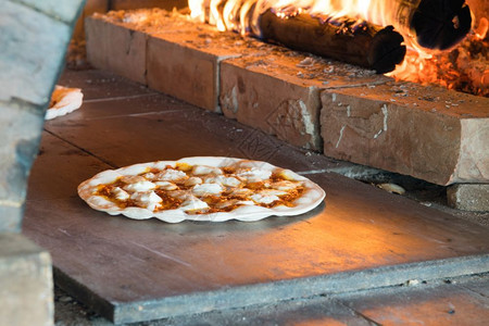 一顿饭烧伤在柴炉中烘烤的薄地壳比萨厨师图片