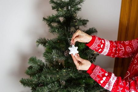 一个穿新年红色毛衣的女孩拿着星形式的圣诞装饰品树新年好精神一个穿着新年红色毛衣的女孩拿着星形式的圣诞装饰品树新年好心情保持手有背景图片