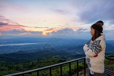 穿着毛衣的女游客在清晨PhuThapBoekViewpointPhetchabun高峰日出时站立观察森林和山区美丽的自然景观看日图片