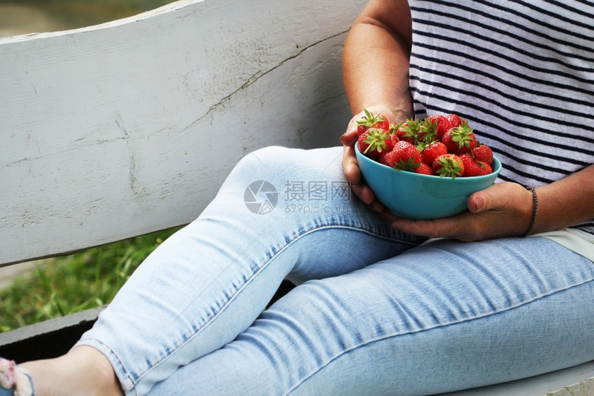 购物者买浆果拿着新鲜草莓的女人夏天背景在长凳上放松女人拿着新鲜草莓夏天背景在长凳上放松图片