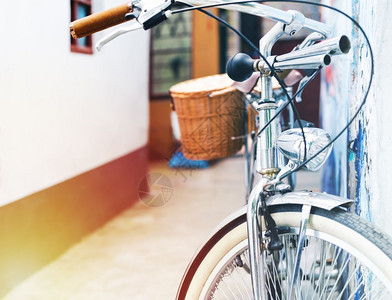 古老的自行车泊靠在房屋墙壁上夏季旧车概念反射行业沥青背景图片