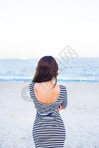 在海滩上穿条纹衣服的女孩回到了在海滩上穿条纹衣服的女孩帽子一种背部图片