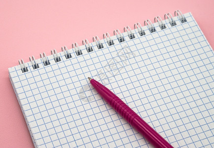 最小的笔记一张空白格子纸记事本和粉红色的笔空白背景图片
