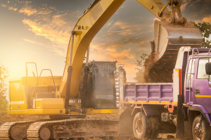 机械通过在建筑工地挖土和向卡车Bucket装载后推土运到卡车Crawler挖土机把倒入重型倾卸卡车挖土机中工程金的图片
