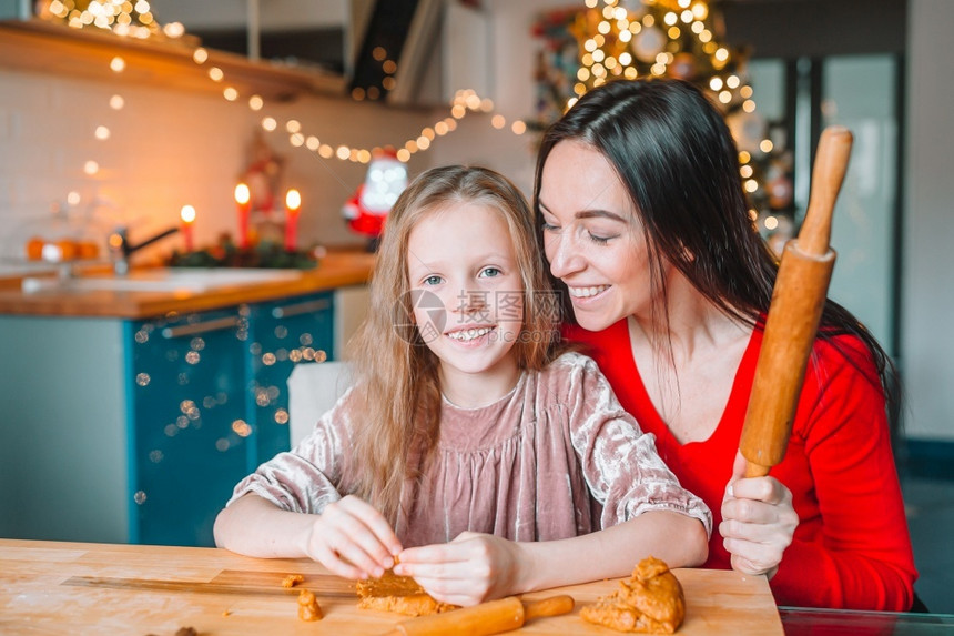 为了烘烤圣诞快乐节日妈和她的女儿们在做圣诞饼干快乐的家庭妈和女儿为圣诞节烤饼干厨房图片