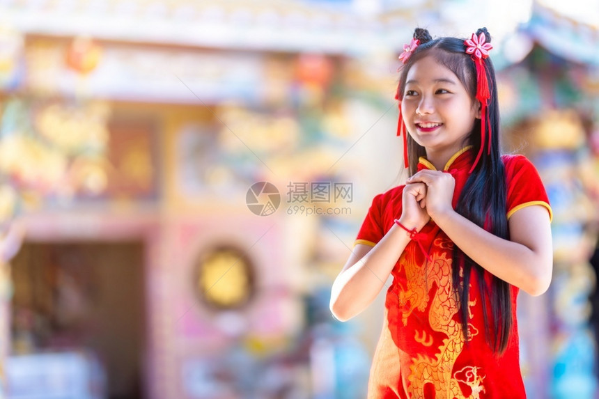 东庆祝孩子身着中华新年节国青春红传统香藏装饰的可爱亚洲小女孩长得一脸美丽的笑并戴着彩礼图片