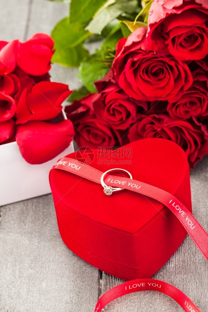 照片来自木制桌子上的环和红玫瑰提议精美的图片