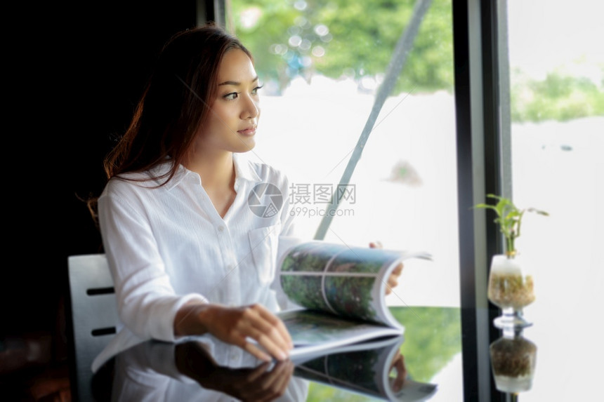 韩国人亚裔女在咖啡厅微笑并阅读一本放松的书活房间图片