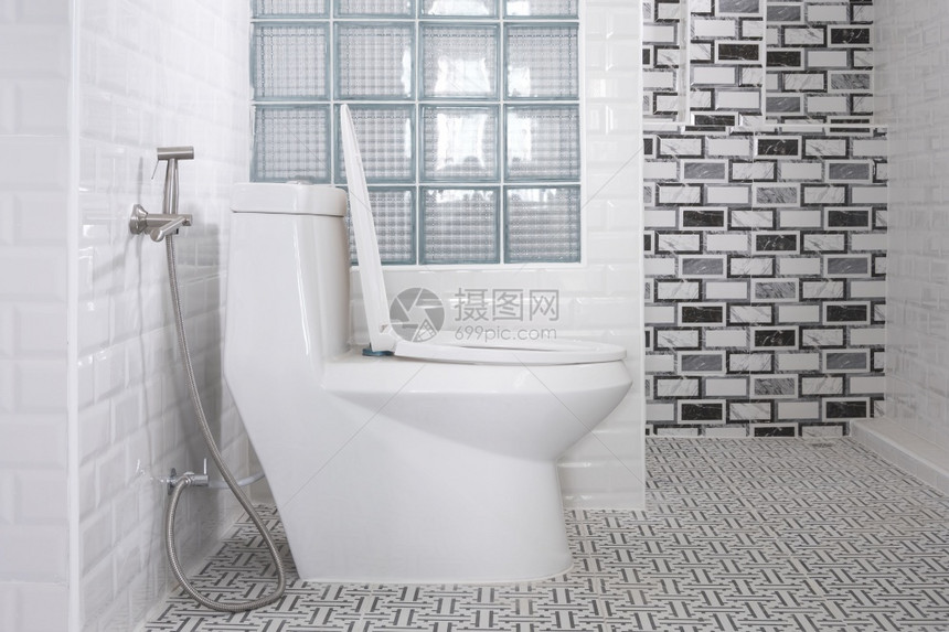 覆盖洗手间白色厕所碗不锈钢板壁喷雾和隔墙中的玻璃块在现代浴室内装有瓷砖墙饰家用室内设计概念部的图片
