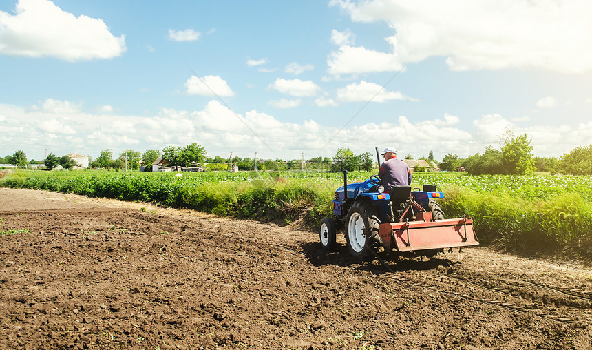 自然农业综合企民驾驶一部拖拉机用磨压碎表面耕种农田业肥沃在种植园田地上研磨和混合土壤为种植新作物准备松动图片