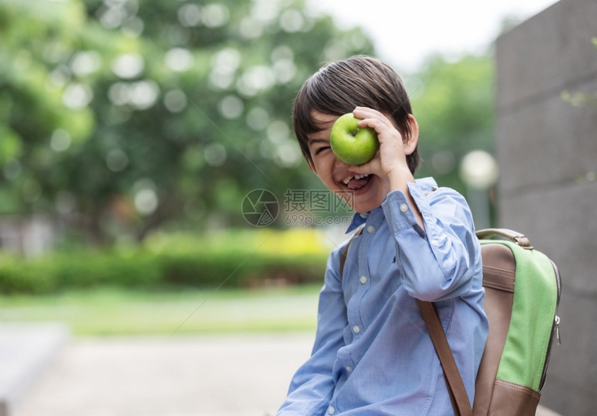携带一个穿着蓝衬衫的可爱小男孩带着一个学生背包展示的苹果在上学前早餐吃布瑞卡法斯特对于儿童发展健康与来说很重要Breakfast图片